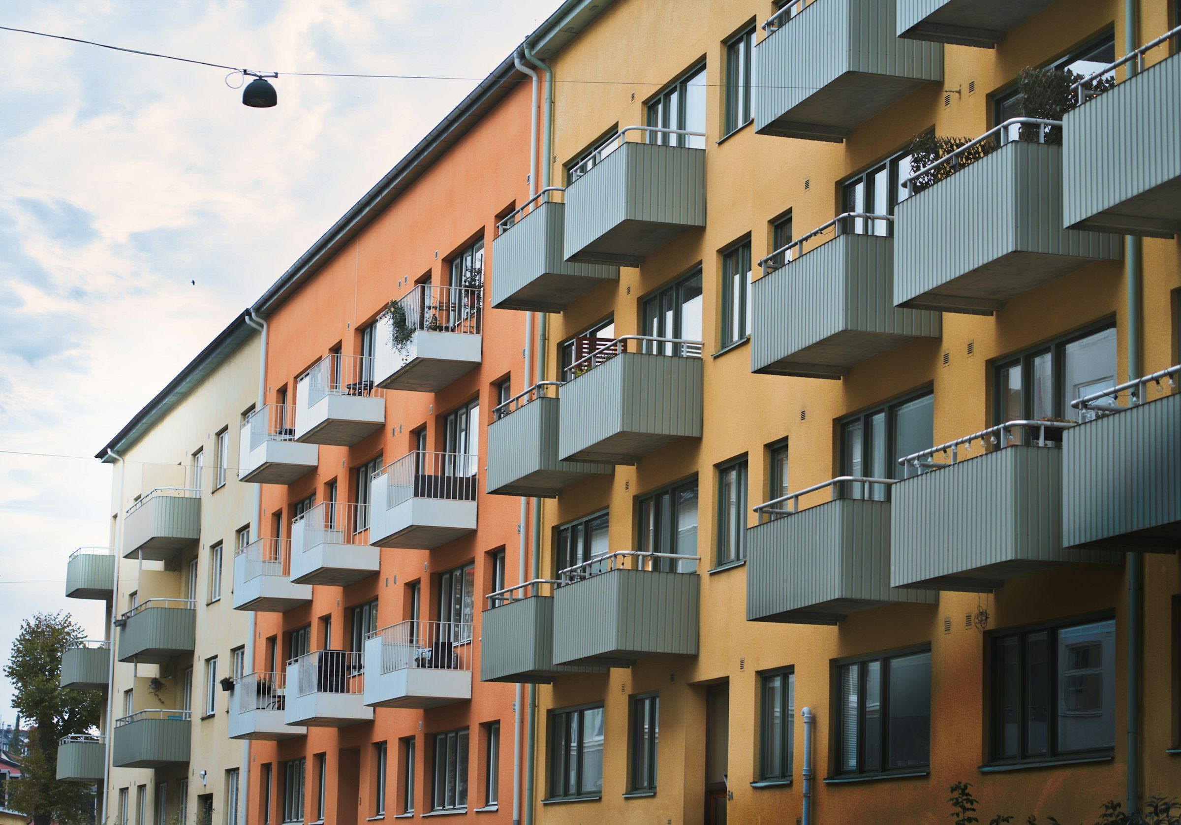 Flerbostadshus i puts med rader av balkonger mot en ljus himmel